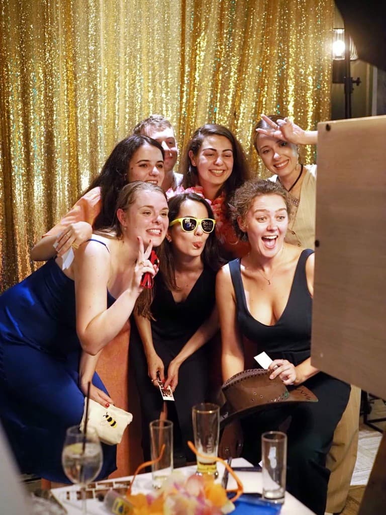 Groupe d'amis qui pose devant un photobooth en soirée